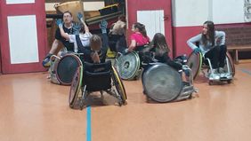 Frauen und M&auml;nner spielen Rugby im Rollstuhl