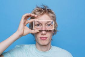 Mann h&auml;lt Smartphone vor sein Gesicht - Gesicht wird durch Smartphone hindurch wiedergegeben