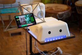 Ein weißer MotionComposer neben einem Notenständer, auf dem ein Tablet mit der MotionComposer-App steht