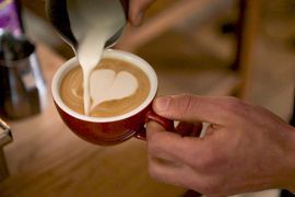 Ein Milchkaffee wird zubereitet und serviert