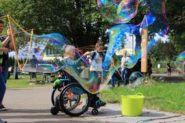 Eine Frau im Rollstuhl, die riesige Seifenblasen aufsteigen l&auml;sst.