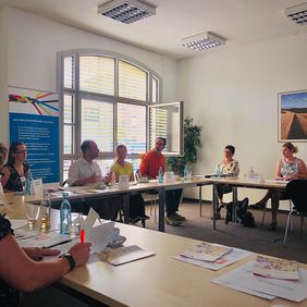 Foto mit Blick auf sitzende Teilnehmer, die im Gespr&auml;ch sind