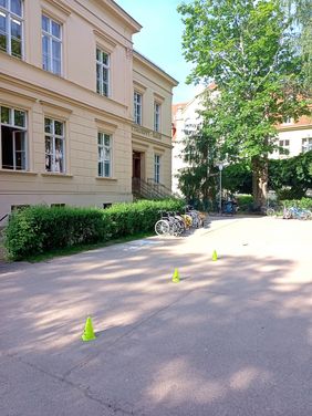 Schulhof Heise Schule Görlitz Der Schulhof der Heise Schule in Görlitz. Auf ndem Schulhof ist ein Rollstuhlparcour mit gelben Kegeln abgesteckt. Vor dem Schulgebäude steht eine Hecke, vor der 4 leere Rollstühle stehen