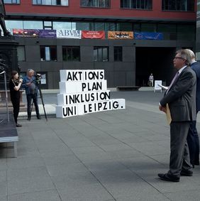 Stephan P&ouml;hler als Zuh&ouml;rer und Blick auf Kartonstapel mit der Aufschrift: Aktionstag Inklusion an der Uni Leipzig
