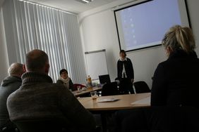 Referentin vor Leinwand - Blick von den sitzenden Teilnehmern aus