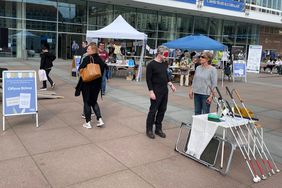 Ein Mann hat eine Maske &uuml;ber den Augen und einen Blindenleitstock in der Hand. Er testet den Blinden-Parcours