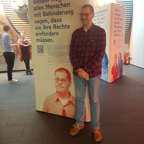 André Brendle vor der Ausstellungswand mit seinem Porträt