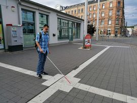 Mann mit Langstock tastet sich am Leitsystem am Neumarkt in Zwickau