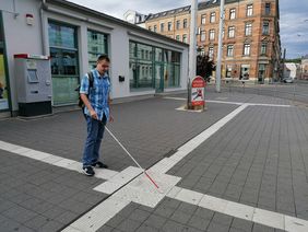 Mann mit Langstock tastet sich am Leitsystem am Neumarkt in Zwickau