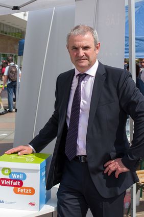 Michael Welsch, der Inklusionsbeauftragte von Sachsen, steht neben der Kiste f&uuml;r die Dummen Fragen. Darauf steht: Weil Vielfalt fetzt.