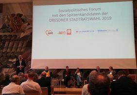 Blick auf Bühne mit Modertor und Podiumsgästen